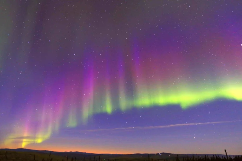 Green and violet northern lights over the snowy flats outside Fairbanks, Alaska, on a moonlight dog sledding, dinner and aurora tour